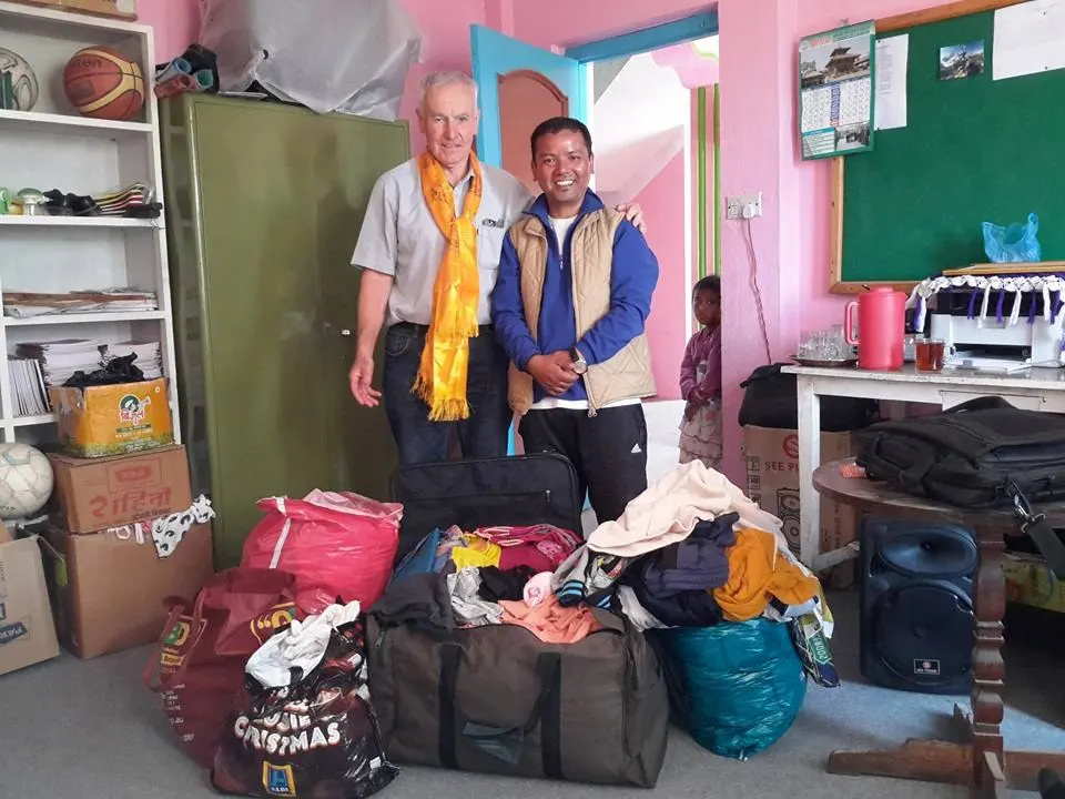 Visitors wearing ceremonial scarves beside bags of donated goods