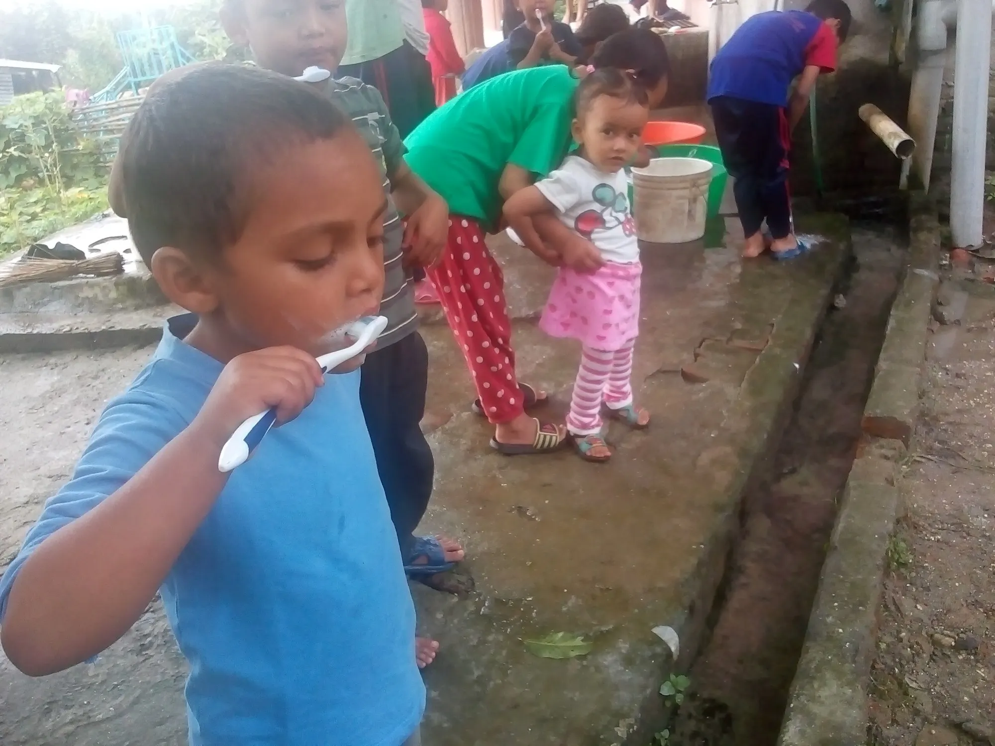 A boy brushing his teeth outdoors in the morning