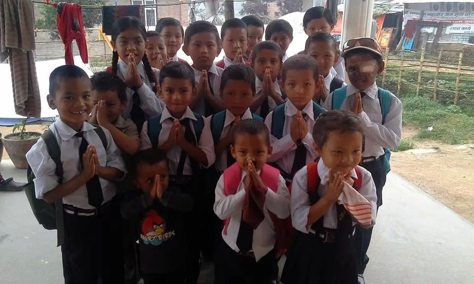Children in school uniform greeting the camera with hands pressed together