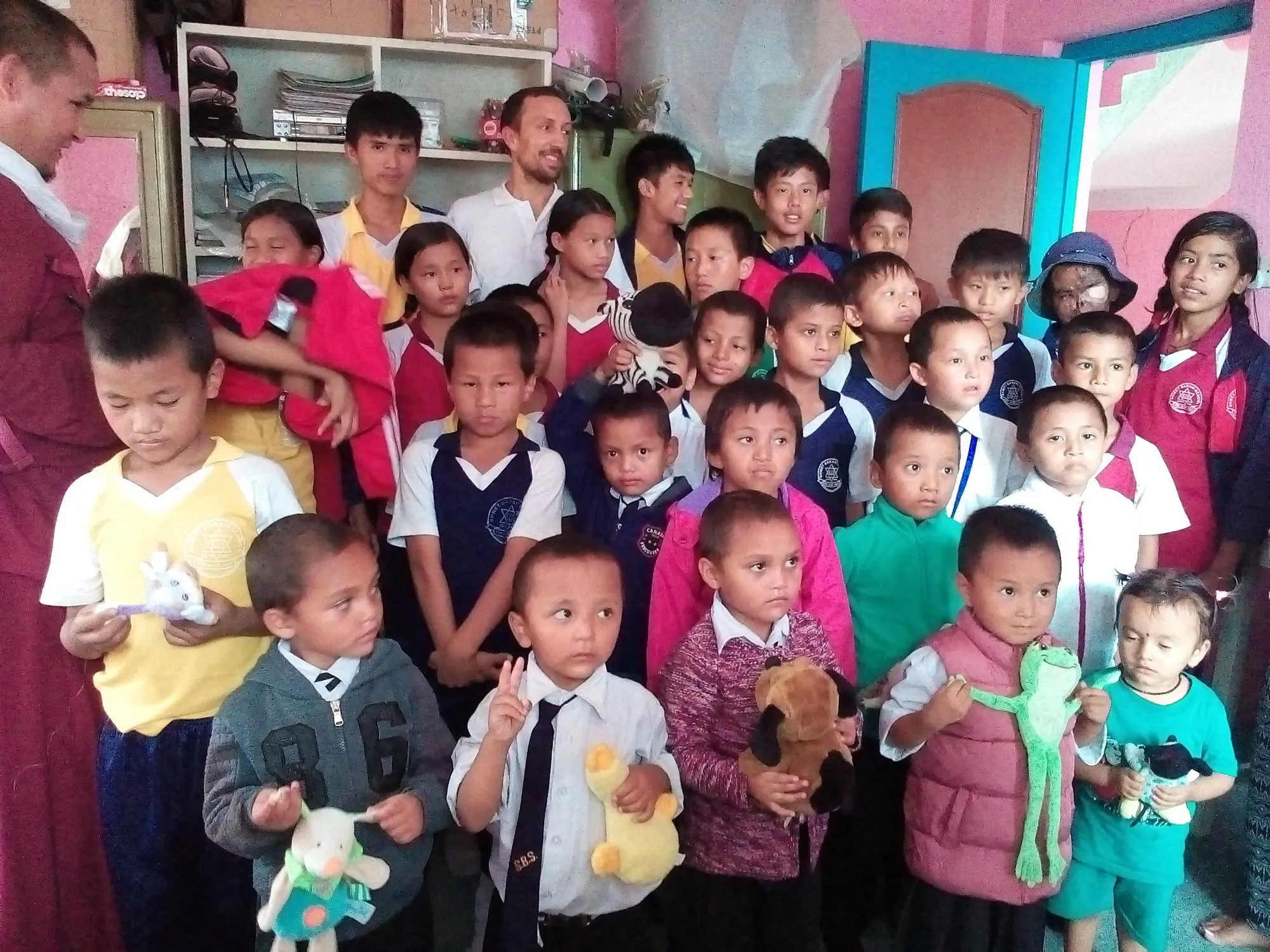 A group of small children with soft toys, standing in a bright room