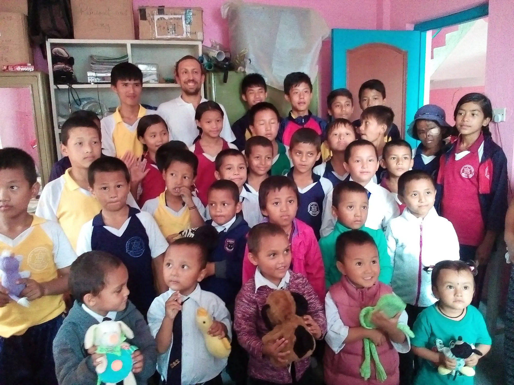 Children indoors holding soft toys they have been given