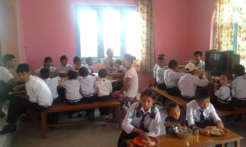 Children sitting at long wooden benches indoors