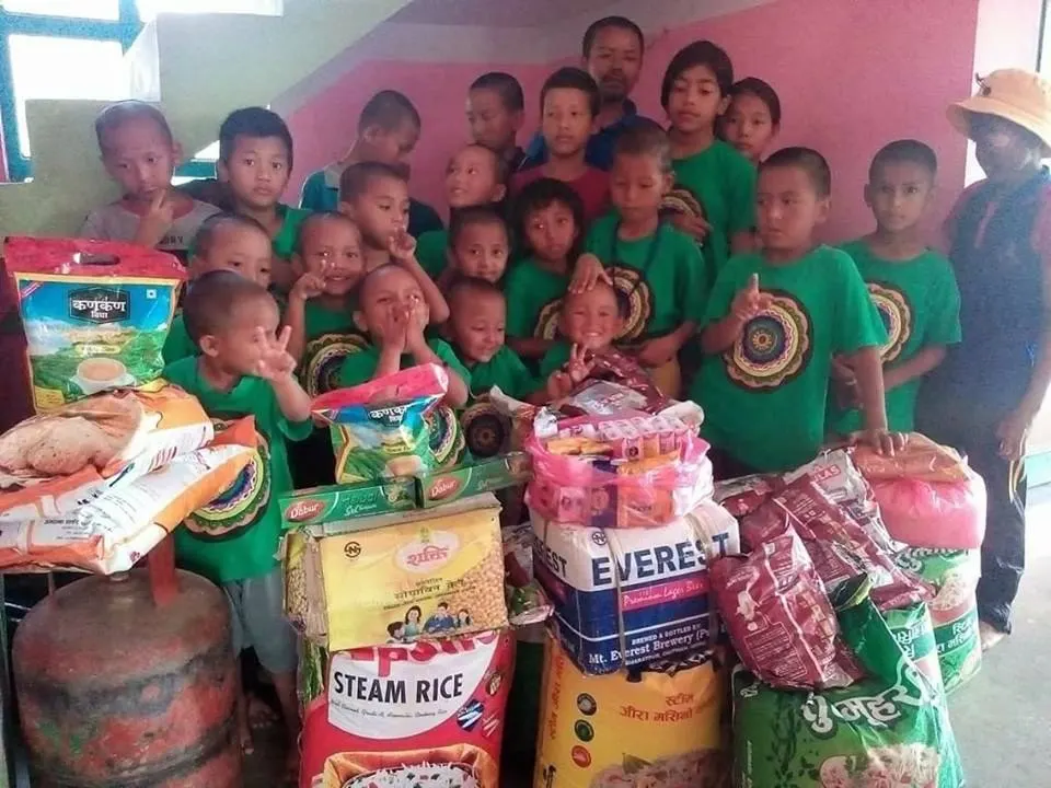 Children standing behind sacks of rice, cooking gas and household supplies that have just been delivered