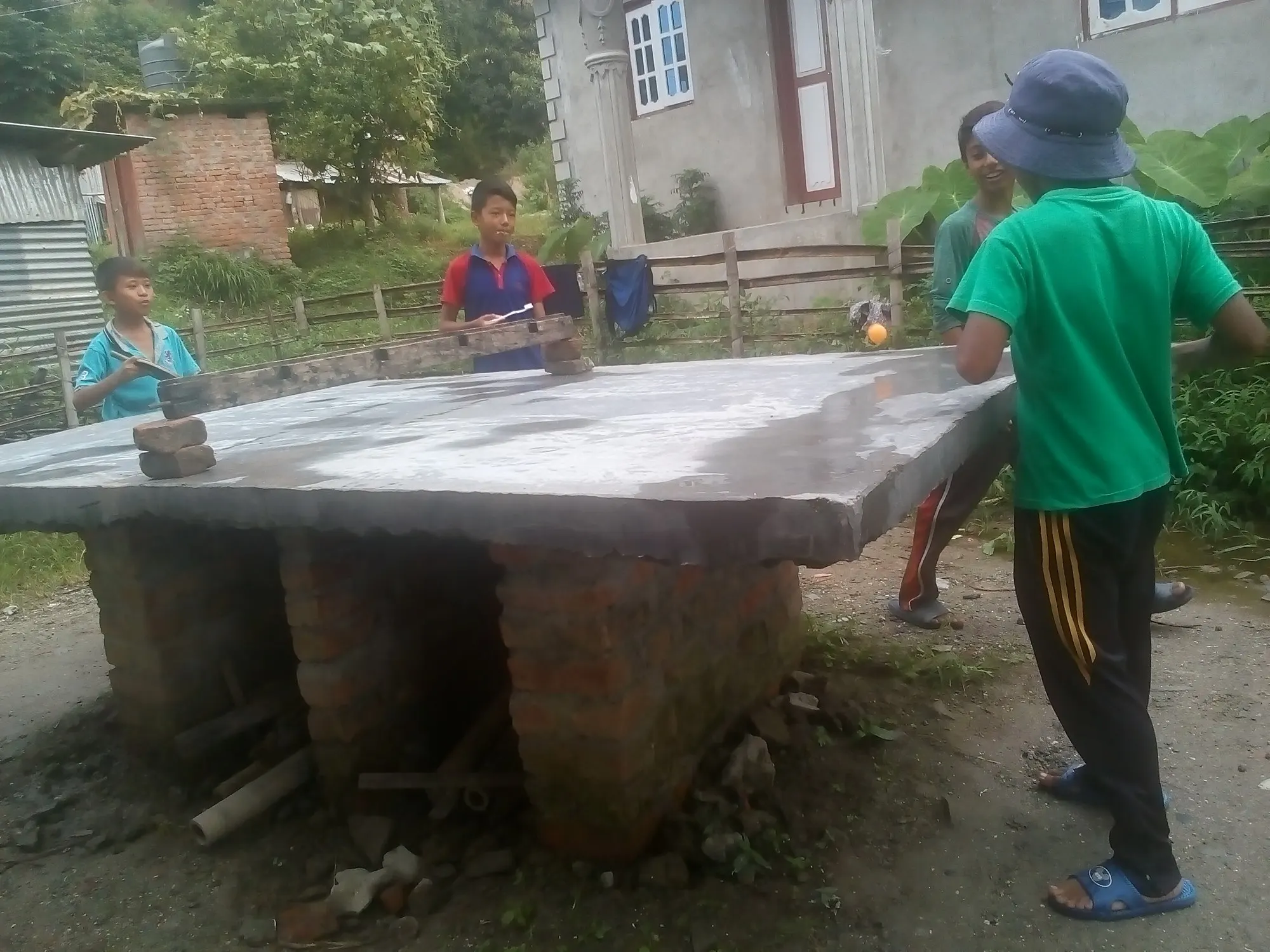 Children playing table tennis on a concrete table in the yard