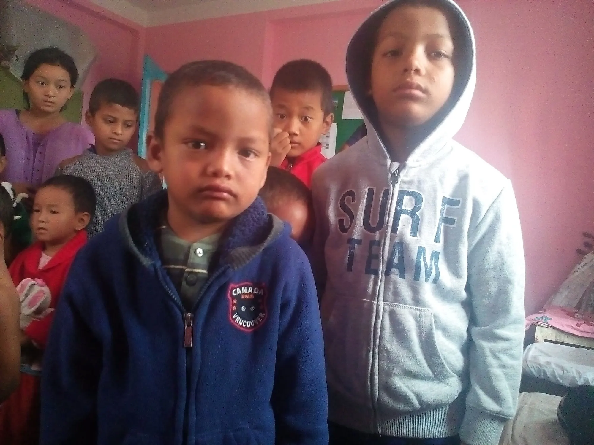 Two boys in warm hooded jackets standing indoors