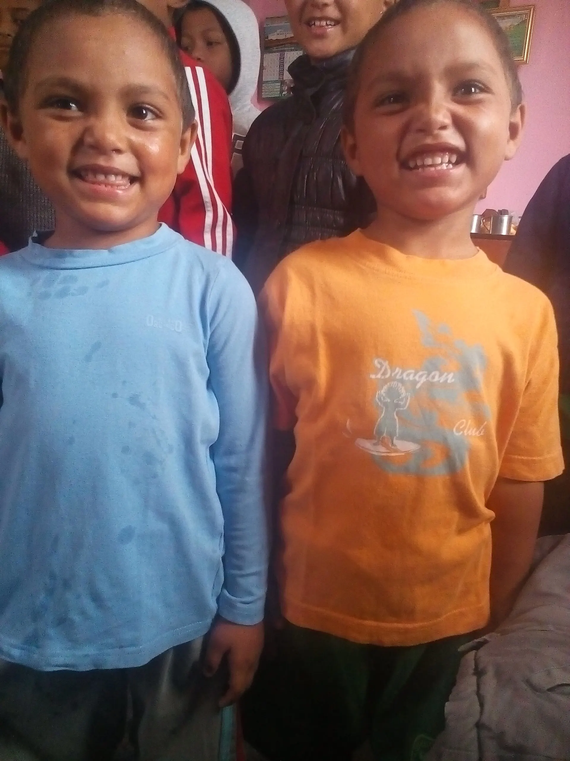 Two small boys standing side by side, both grinning