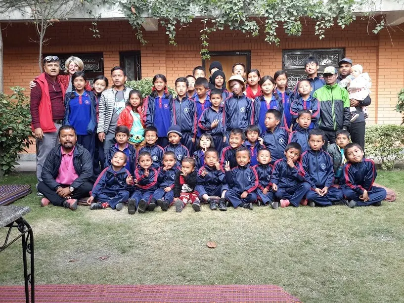 A large group photograph of the children together with visiting supporters in a garden